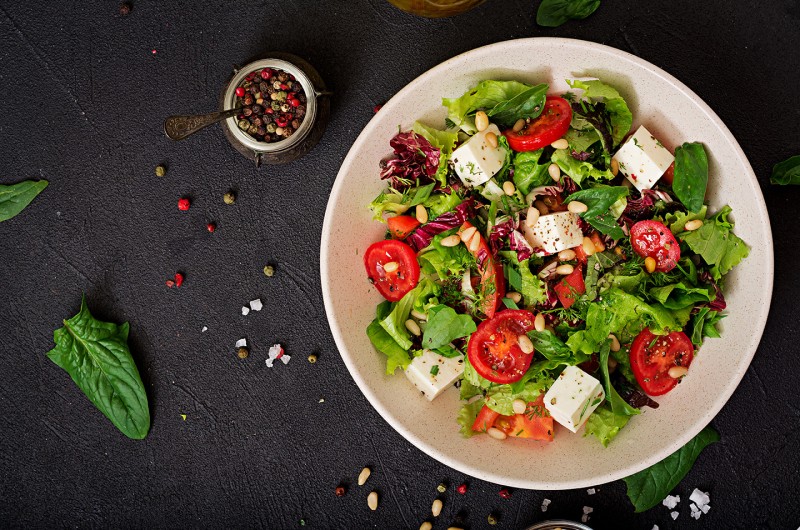 dietary salad with tomatoes feta lettuce spinach pine nuts top view flat lay