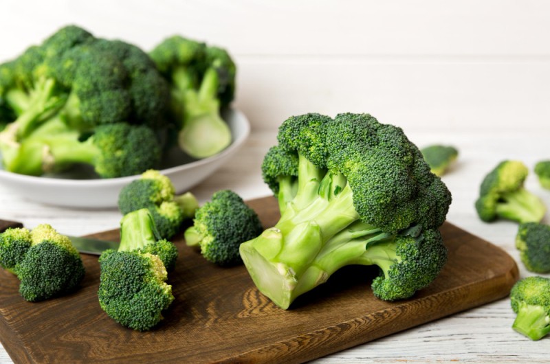 fresh green broccoli wooden cutting board with knife broccoli cabbage leaves light background flat lay 1